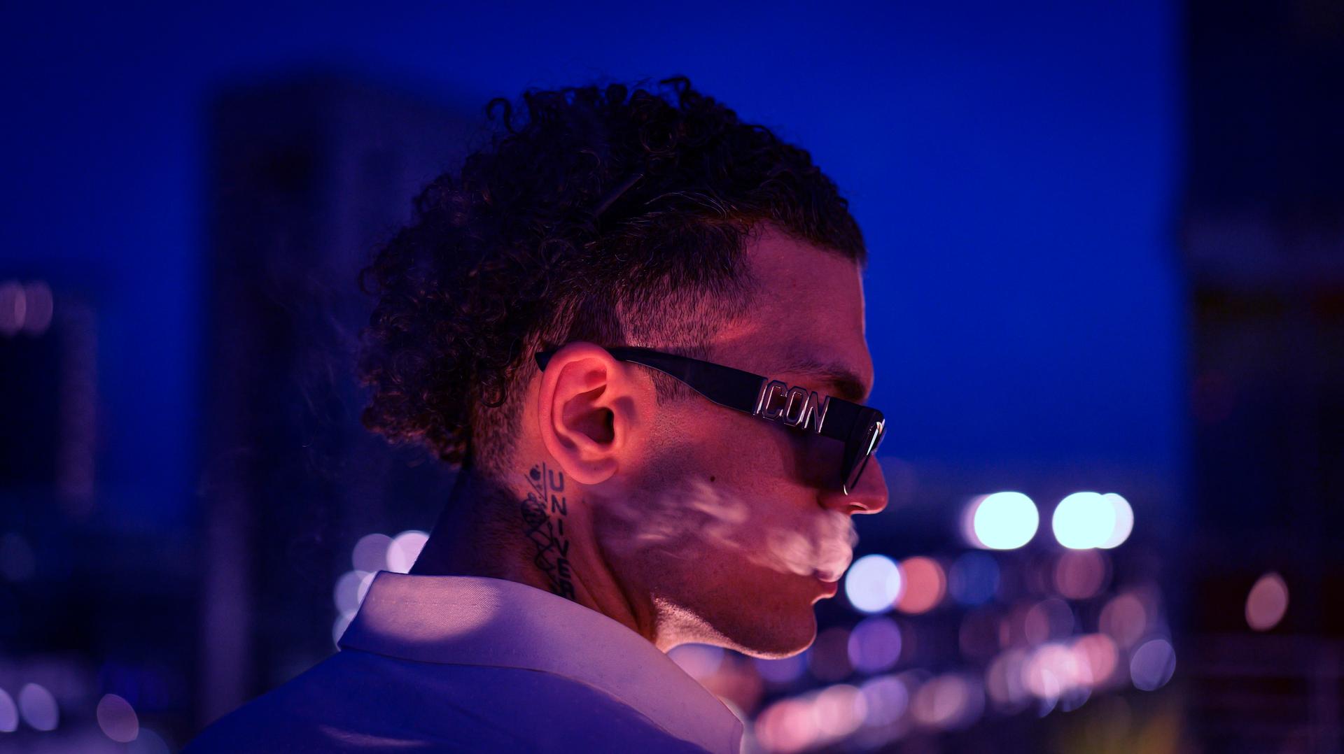 side profile and cigar smoke with the city shining in the background